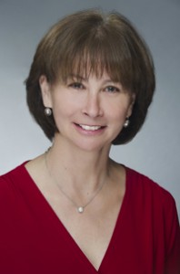 Headshot of Donna Martin in a red sweater with a gray background